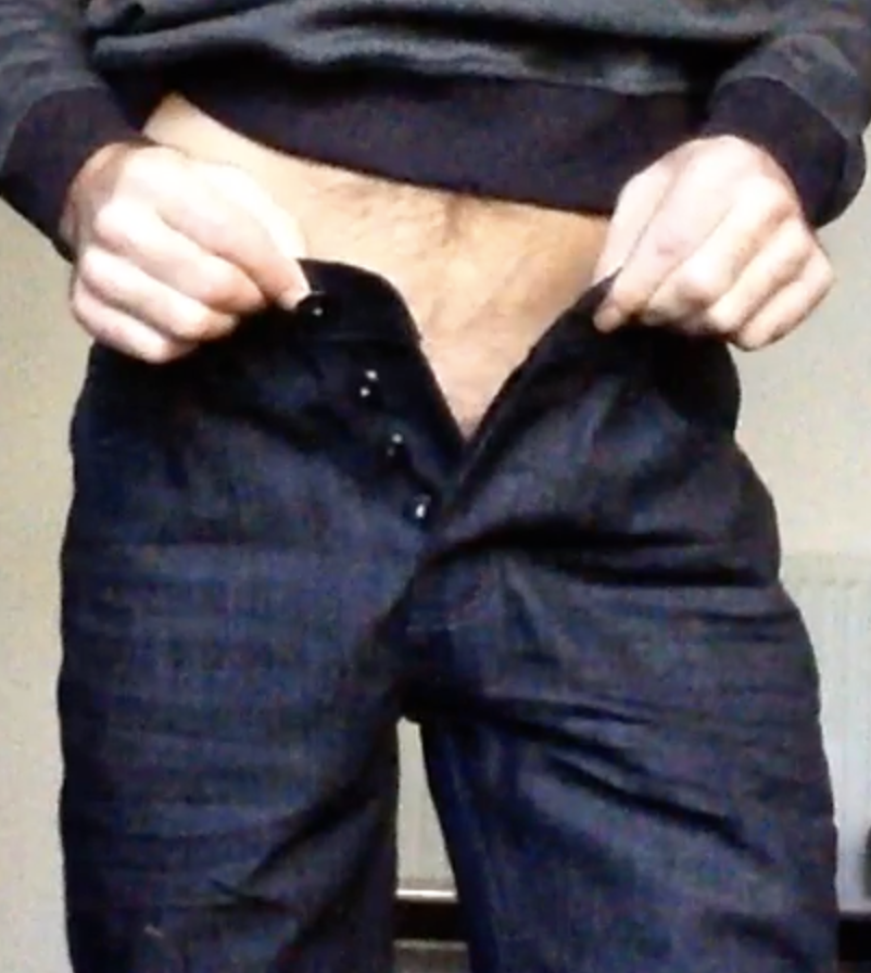 Man with unbuttoned jeans as if to hide his penis