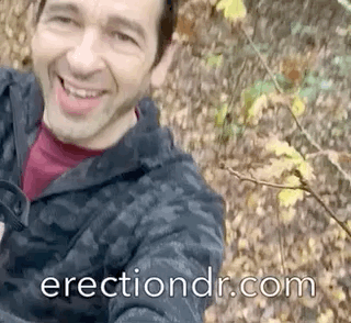 a man outdoors running part naked with his penis out soft and semi erect with a happy expression